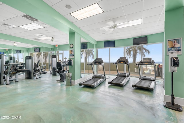gym featuring baseboards, visible vents, a drop ceiling, and ceiling fan
