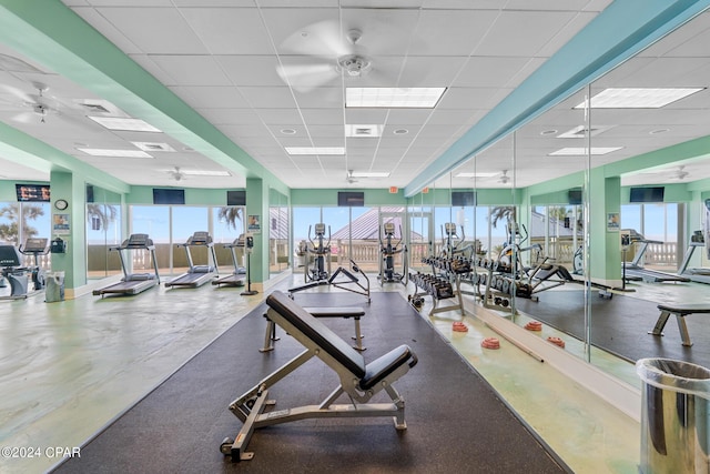 workout area with a drop ceiling, visible vents, baseboards, and ceiling fan