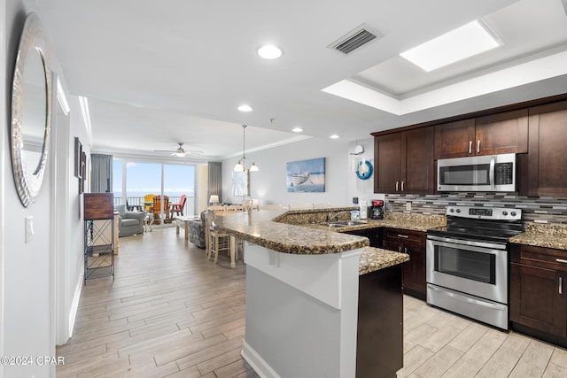 kitchen featuring stainless steel appliances, a peninsula, visible vents, wood tiled floor, and tasteful backsplash