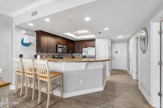 kitchen featuring light stone counters, visible vents, light wood-style floors, appliances with stainless steel finishes, and decorative backsplash