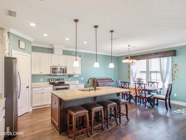 kitchen featuring dark wood finished floors, a center island with sink, stainless steel appliances, visible vents, and a sink