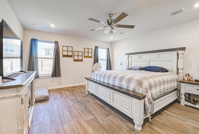 bedroom with a textured ceiling, baseboards, visible vents, and light wood-type flooring