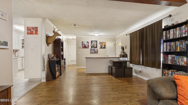 interior space with visible vents, crown molding, a textured ceiling, and wood finished floors