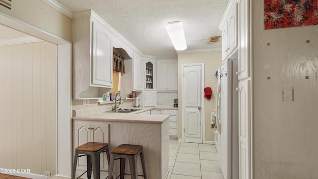 kitchen featuring light countertops, light tile patterned flooring, a sink, a peninsula, and a kitchen breakfast bar