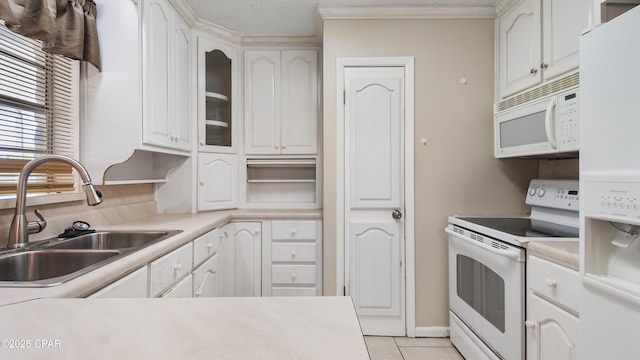 kitchen featuring light countertops, white appliances, white cabinetry, a sink, and light tile patterned floors
