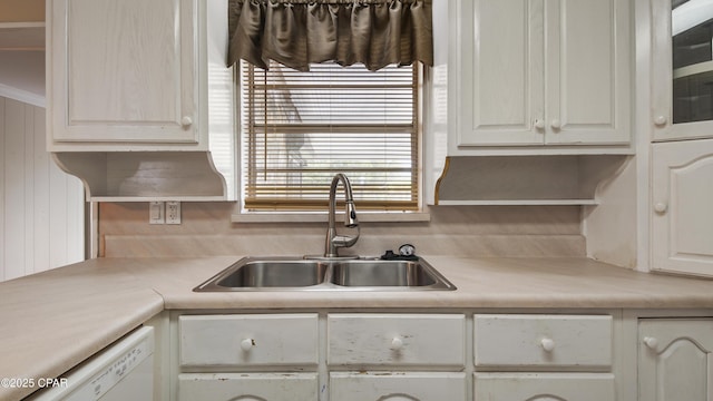 kitchen featuring white cabinetry, light countertops, crown molding, a sink, and white dishwasher