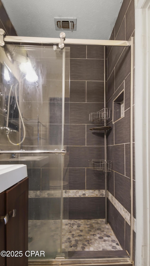 full bath with a shower stall, visible vents, and vanity