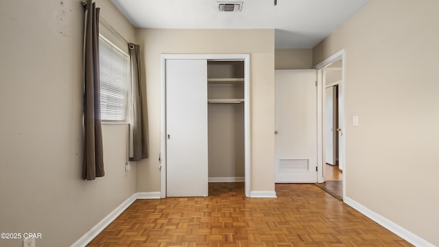 unfurnished bedroom with baseboards, visible vents, and a closet