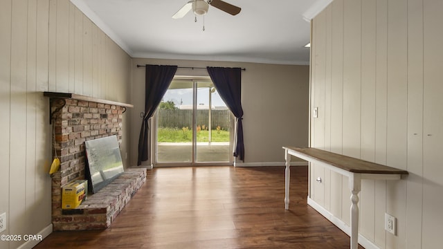unfurnished living room featuring crown molding, a fireplace, wood finished floors, baseboards, and ceiling fan