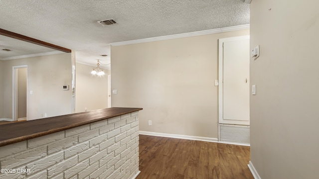 interior space with a textured ceiling, visible vents, ornamental molding, dark wood-type flooring, and a dry bar