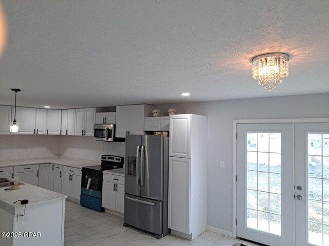 kitchen with light stone counters, french doors, decorative light fixtures, appliances with stainless steel finishes, and white cabinets