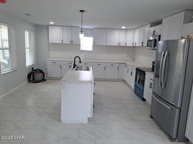 kitchen featuring stainless steel appliances, a wealth of natural light, a sink, and a center island with sink