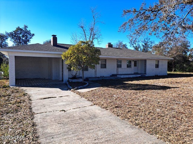 single story home with a garage, a chimney, concrete driveway, and brick siding