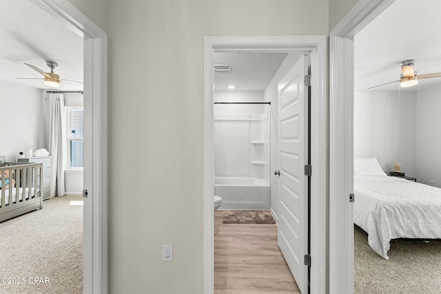 bedroom featuring a ceiling fan, light colored carpet, and connected bathroom