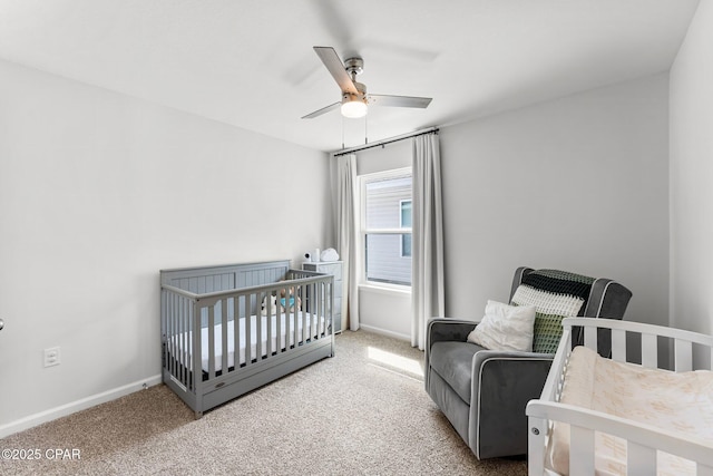 bedroom featuring ceiling fan, a crib, carpet, and baseboards