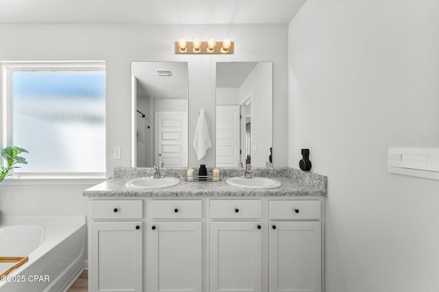 full bath featuring double vanity, a sink, and a bath