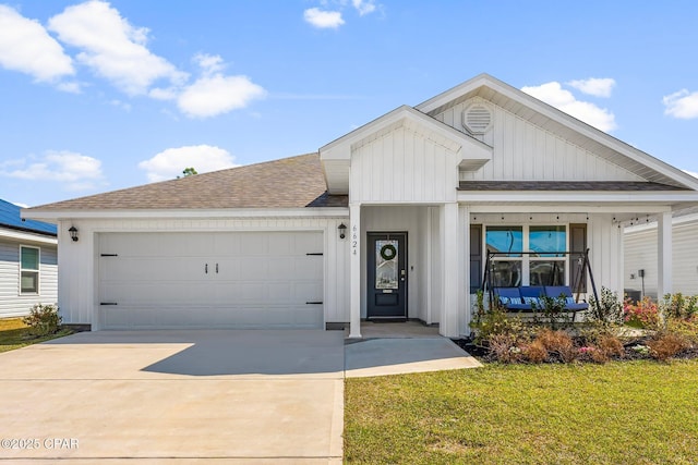 view of front of house featuring an attached garage, a front yard, concrete driveway, and roof with shingles