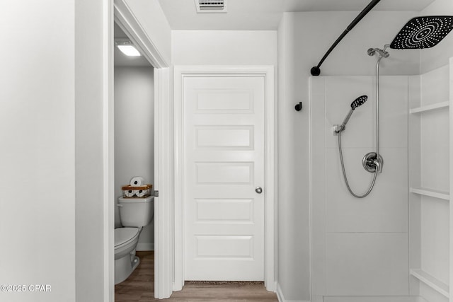 bathroom featuring a shower, visible vents, toilet, and wood finished floors