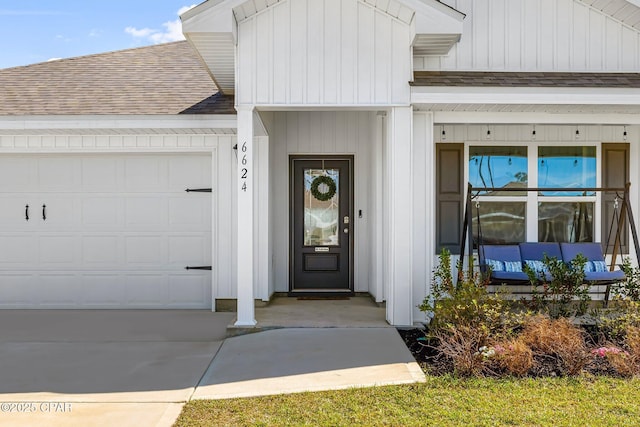 doorway to property featuring a garage, board and batten siding, a shingled roof, and concrete driveway