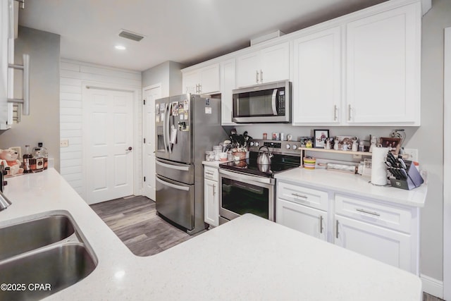 5429 Blue Dog Rd, Panama City, FL 32404 - kitchen with appliances with stainless steel finishes, a sink, white cabinetry, wood finished floors, and recessed lighting