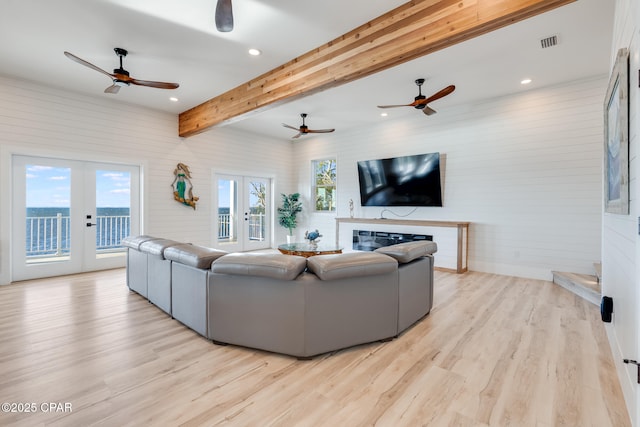 living area featuring french doors, beamed ceiling, visible vents, and light wood-style floors