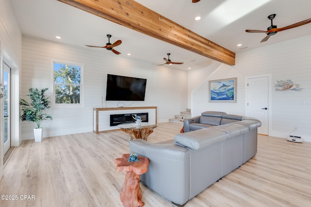 living area with a glass covered fireplace, vaulted ceiling with beams, light wood-style flooring, and recessed lighting