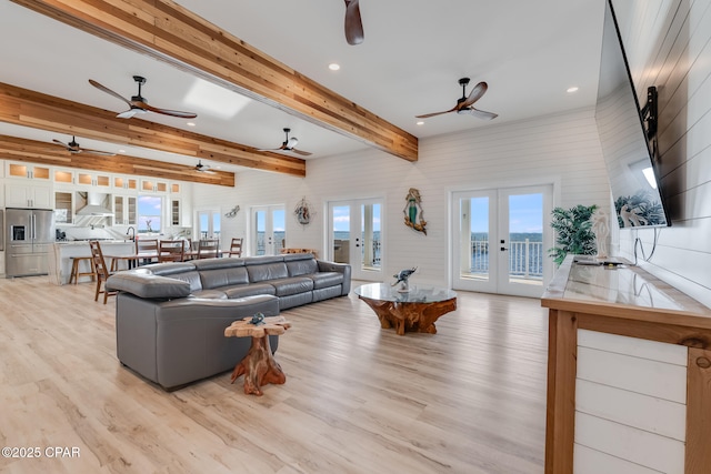 living room with light wood finished floors, recessed lighting, beamed ceiling, and french doors