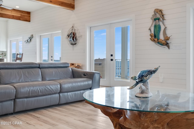 living area with light wood-style flooring, beam ceiling, and french doors