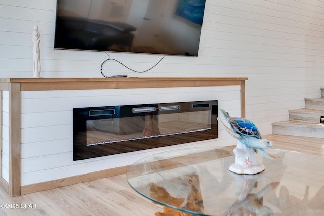 room details with wooden walls, wood finished floors, and a glass covered fireplace