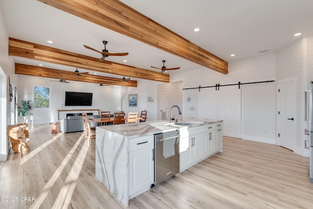 kitchen featuring a barn door, light wood-style flooring, white cabinetry, beam ceiling, and dishwasher