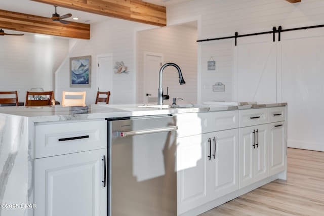 kitchen with a barn door, dishwasher, beamed ceiling, light wood-type flooring, and a sink