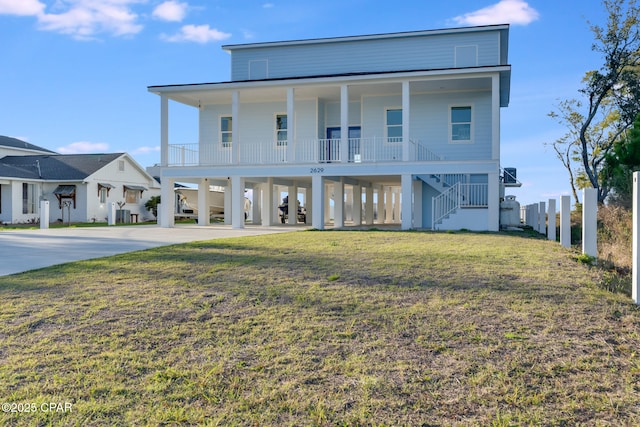 view of front facade featuring covered porch, stairs, concrete driveway, a carport, and a front lawn