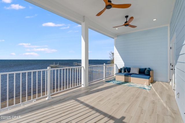 wooden deck featuring outdoor lounge area, a water view, and a ceiling fan