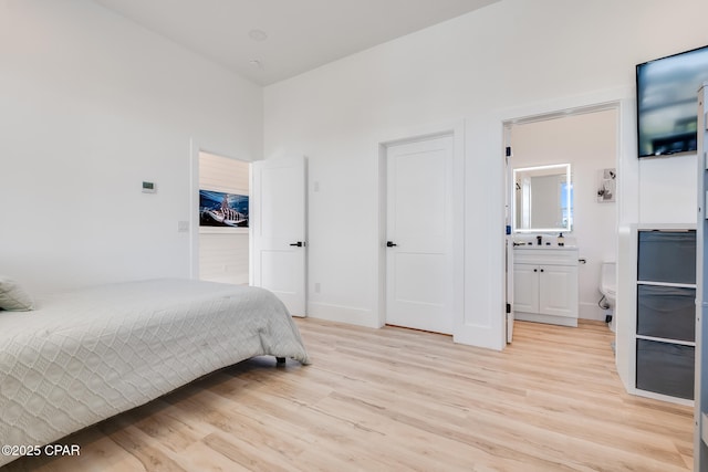 bedroom with ensuite bathroom and light wood-style flooring