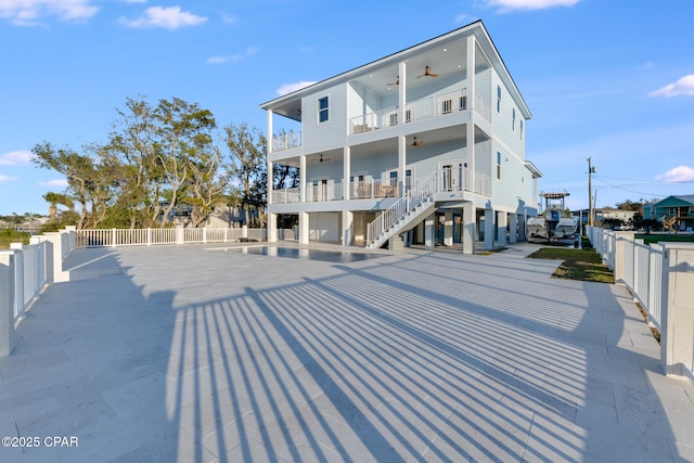 rear view of house with a balcony, a fenced backyard, stairway, and a ceiling fan