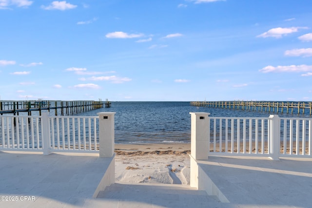 view of dock with a water view and a beach view