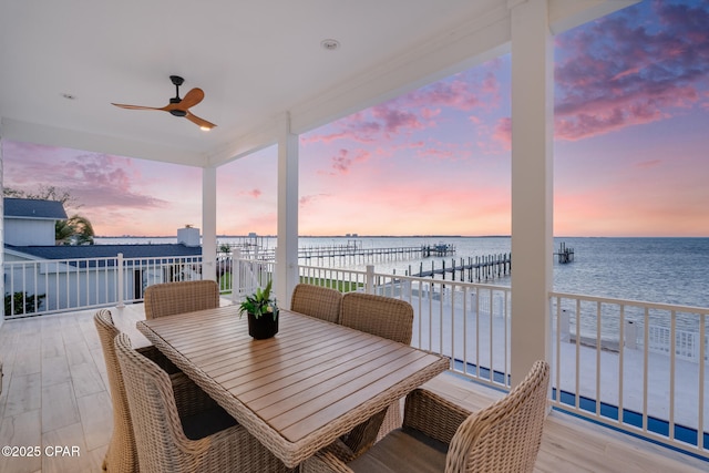 exterior space featuring outdoor dining area, a water view, and a ceiling fan