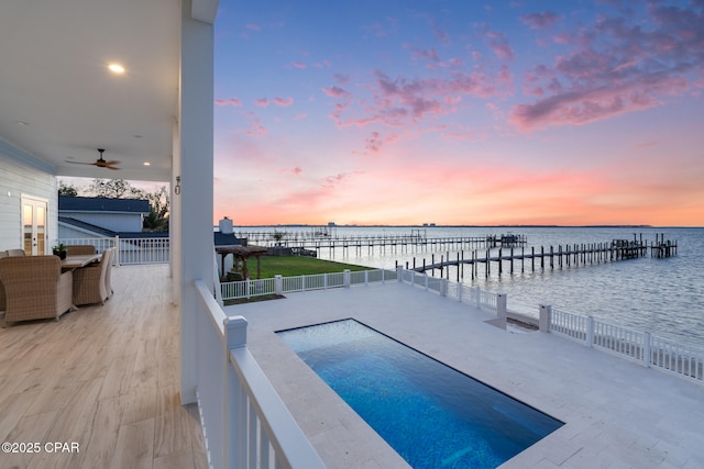 pool at dusk with a dock and a water view