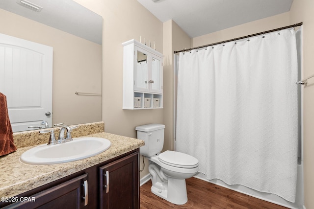 full bath with toilet, visible vents, wood finished floors, and vanity