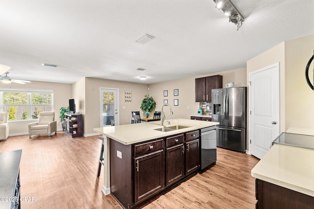 kitchen featuring dark brown cabinetry, stainless steel appliances, a sink, visible vents, and light countertops