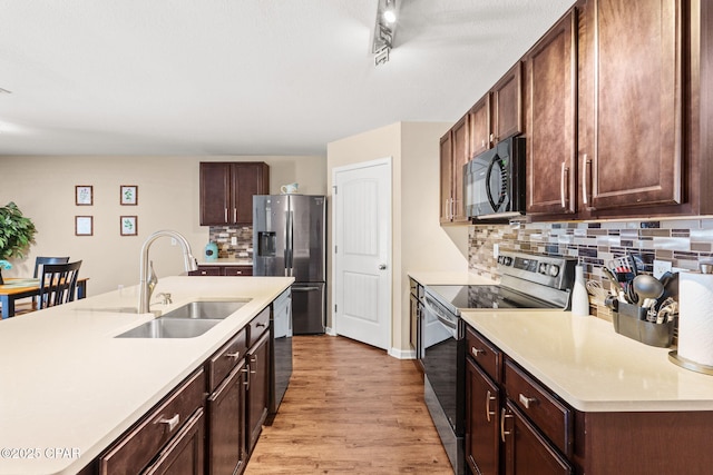 kitchen with appliances with stainless steel finishes, light countertops, a sink, and light wood-style flooring