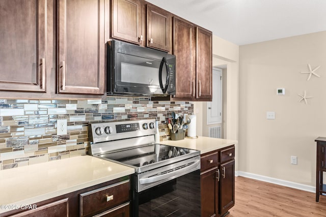 kitchen with light wood-style flooring, decorative backsplash, stainless steel range with electric cooktop, black microwave, and baseboards