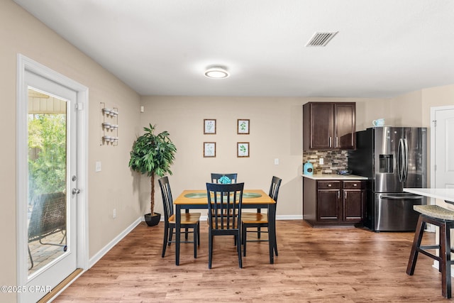 dining space with visible vents, light wood-style flooring, and baseboards