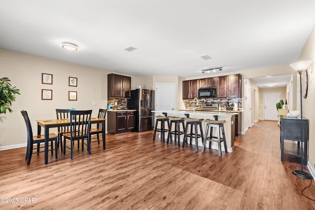 dining space with baseboards, visible vents, and light wood finished floors