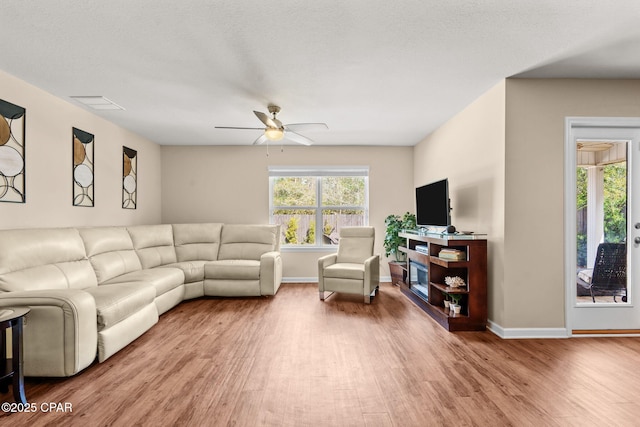 living area with baseboards, wood finished floors, and a healthy amount of sunlight