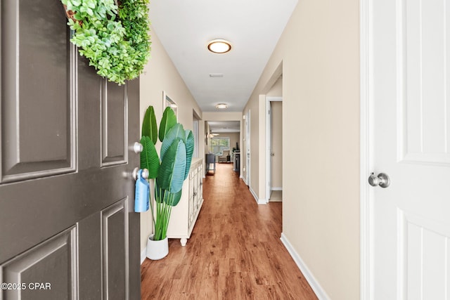 hall featuring baseboards and light wood finished floors