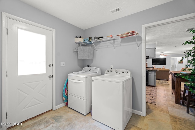 washroom featuring a textured ceiling, laundry area, separate washer and dryer, visible vents, and baseboards