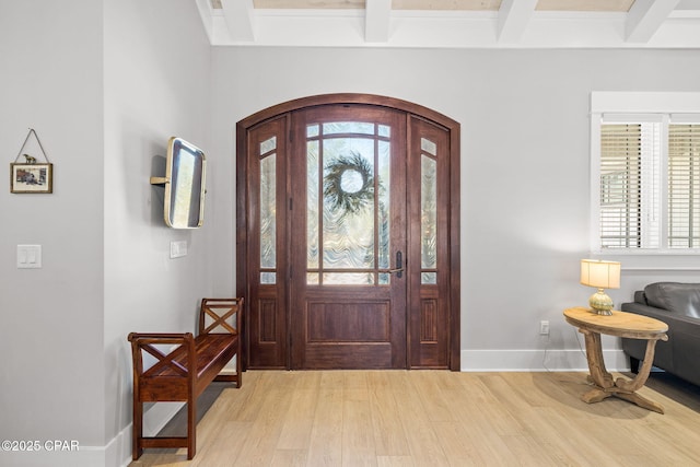 foyer with light wood-type flooring, baseboards, and beamed ceiling