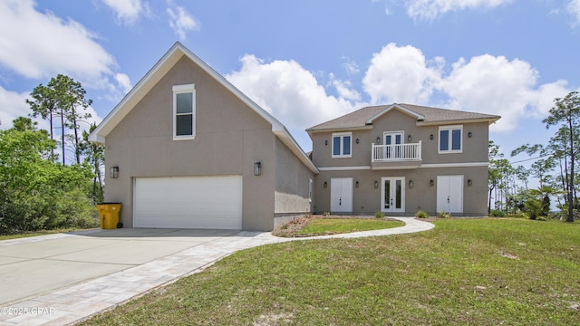 view of front of house with a balcony, stucco siding, a front yard, and french doors