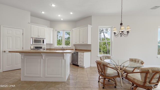 kitchen with appliances with stainless steel finishes, visible vents, a kitchen bar, and white cabinetry